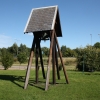  På gräsmattan på gården står klockstapeln.