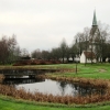 En vacker och rogivande konstgjord vattensamling med bryggövergång i kyrkans regi.