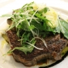 Entrecôte på bädd av grönsaker, toppad med ruccola och vitlökssmör