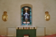 Altaret flankerat av bänkar och med en glasmålning av Albert Eldh som altartavla (1927)