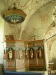 Den romanska dopfunten med en biskopsrelief och en kvadratisk stentavla i bakgrunden